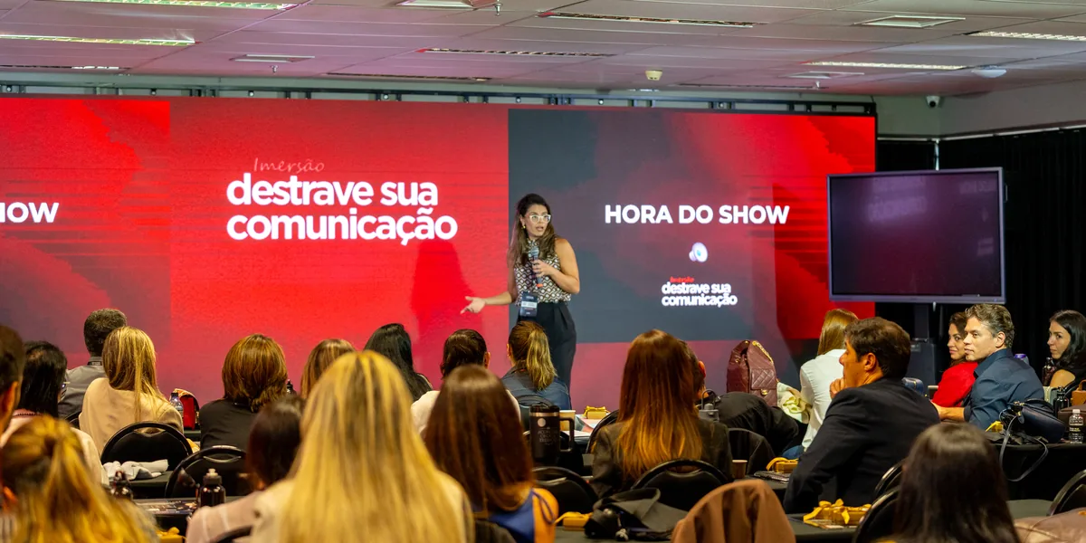 Participante no palco com o microfone, diante da plateia, no momento Hora do Show