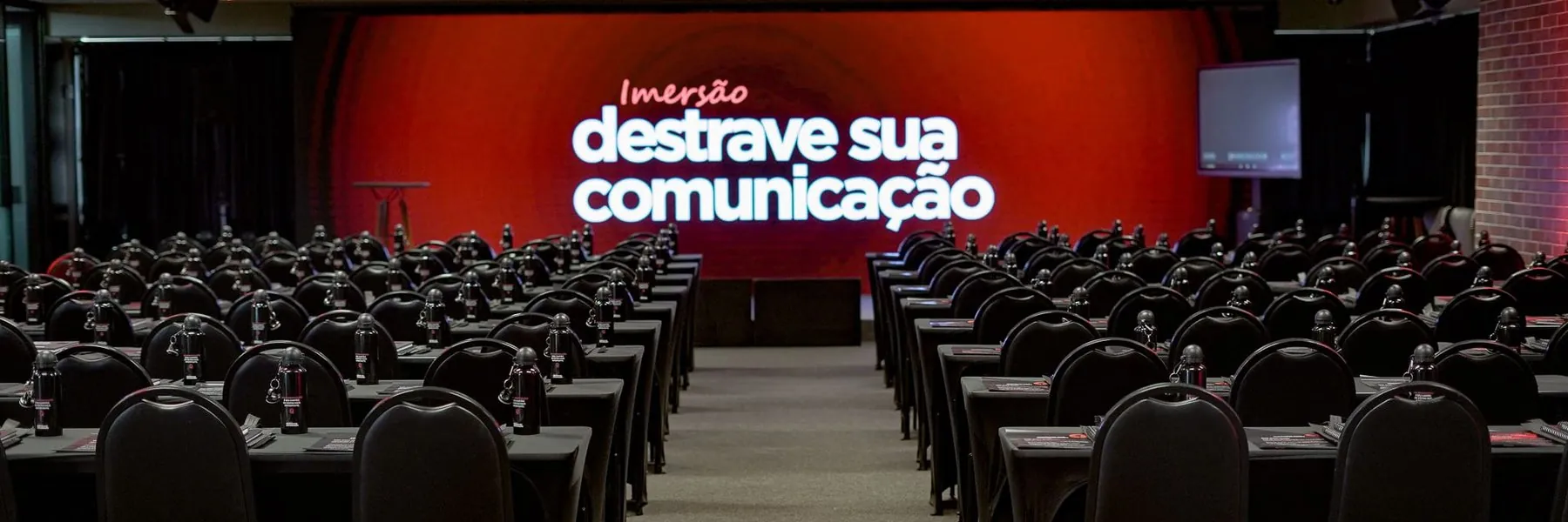 Sala montada antes do evento, com o telão da imersão Destrave Sua Comunicação ao fundo